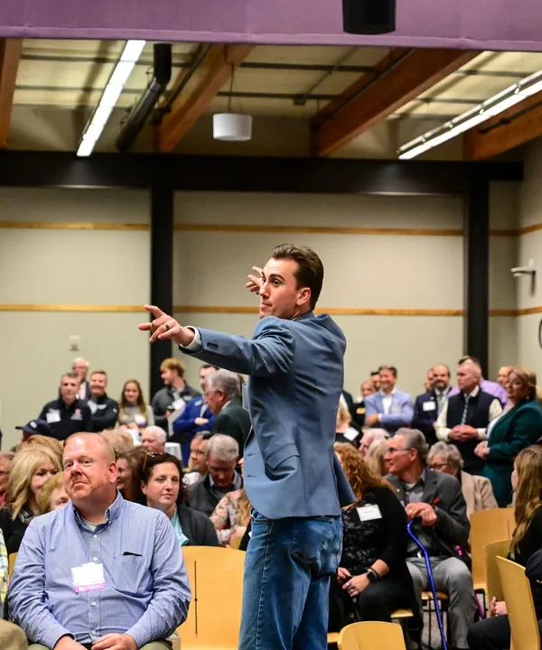 Speaker addresses audience at crowded conference event.