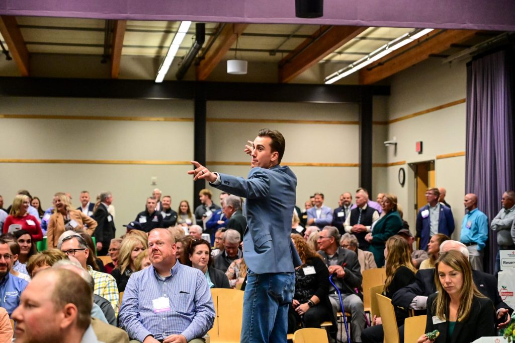 Speaker addresses audience at crowded conference event.