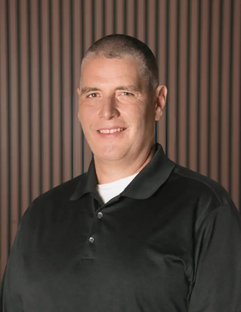 Smiling person in black shirt, striped background.