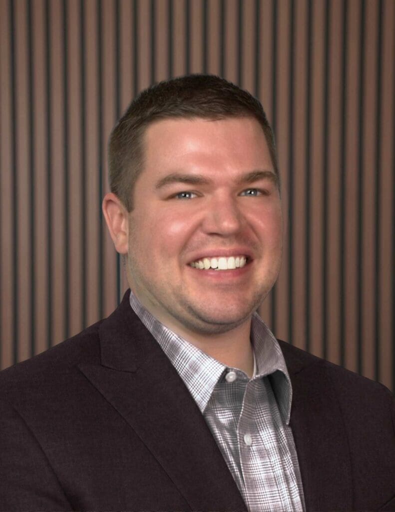 Smiling person in business attire with striped background.