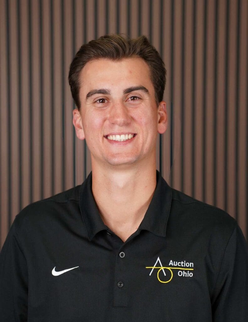 Smiling person in black Auction Ohio shirt.