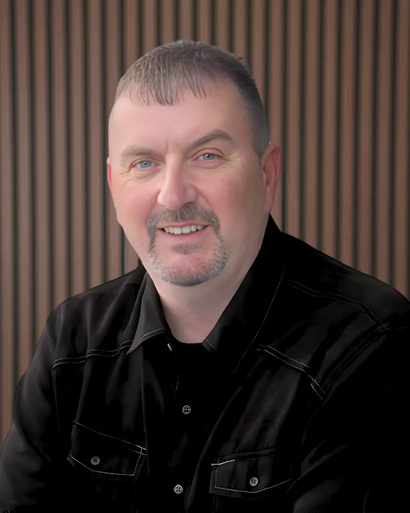 Smiling man in black shirt with wood background