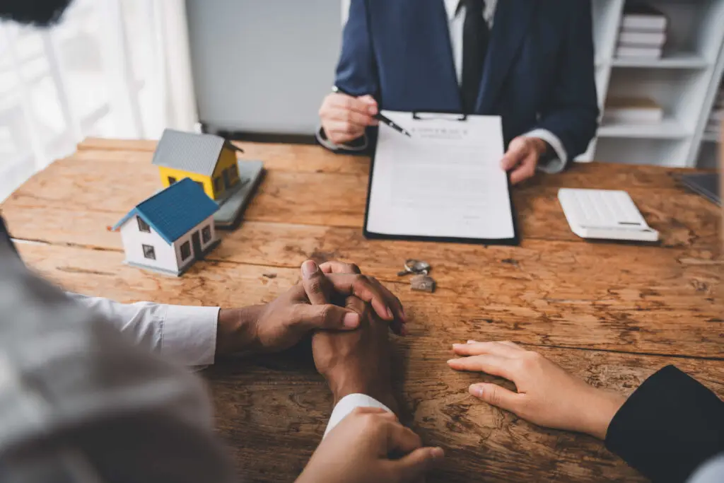 Couple signing home purchase agreement with agent