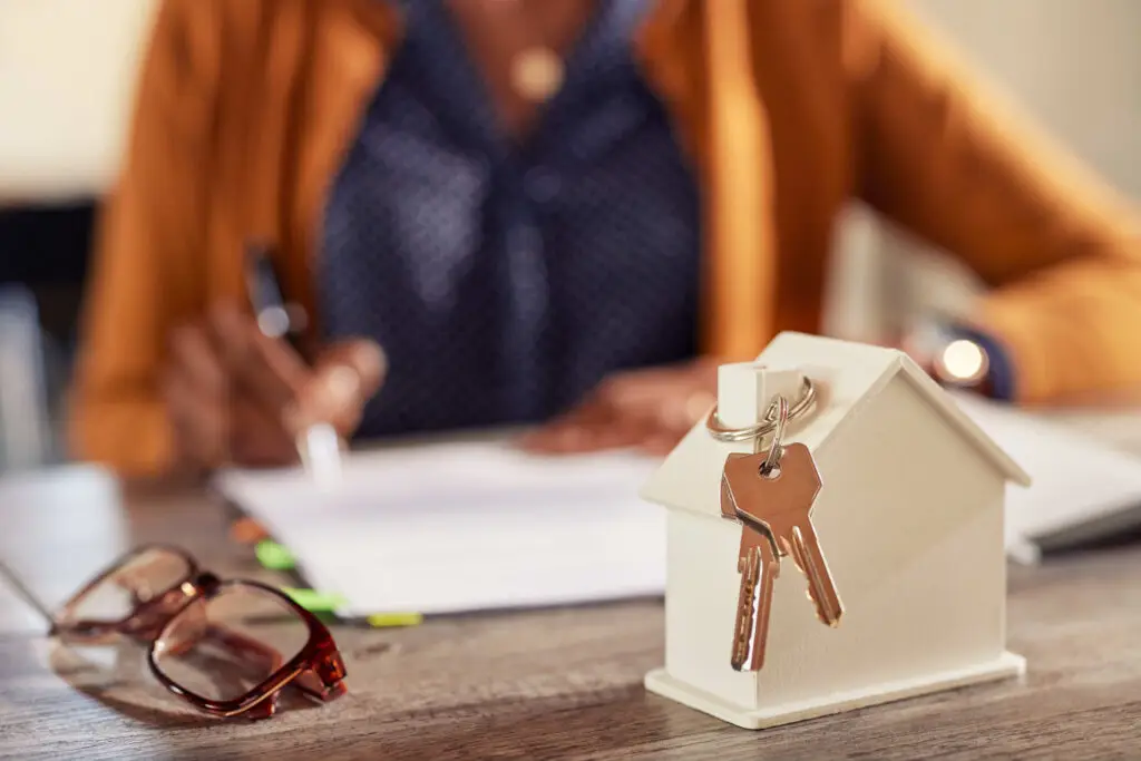 House model with keys and paperwork signing